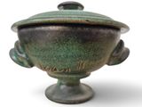 un vase vert avec un couvercle sur fond blanc