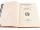 an open book sitting on top of a white table next to a tassel