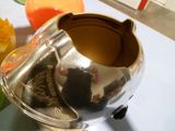 une théière en argent posée sur une table à côté de quelques fleurs