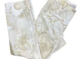 Le pantalon est blanc et doré, avec un motif floral.
