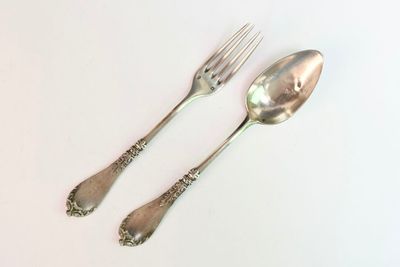 deux cuillères et une fourchette en argent sur une surface blanche