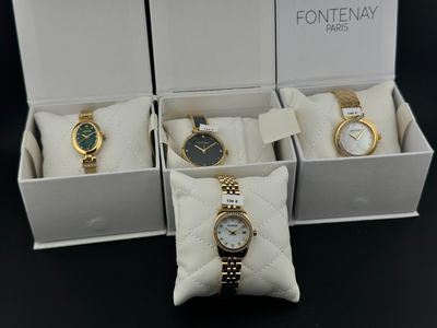 trois montres dans une boîte avec un coussin, et un coussin posé sur une table