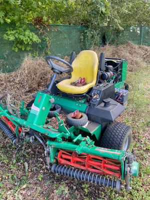 a lawn mower sitting in the grass next to a pile of mulch