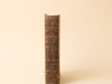 un vieux livre posé sur une table à côté d'un mur blanc