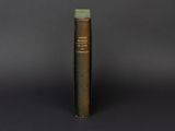 an old book with a green cover sitting on top of a table