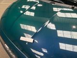 a green car with a sticker on it parked in a parking lot