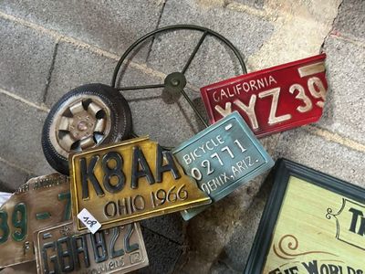 un tas de plaques d'immatriculation par terre, à côté d'une roue