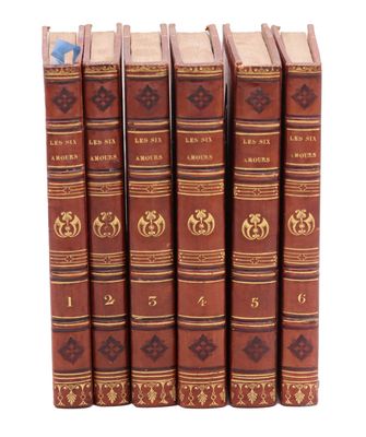 six vieux livres sont empilés sur une surface blanche