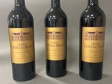 trois bouteilles de vin posées sur une table l'une à côté de l'autre