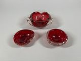 three red glass bowls and a bowl on a white surface