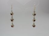 a pair of silver earrings with garnets on them