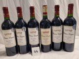 six bottles of red wine are lined up on a table