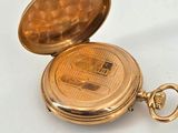 a gold pocket watch sitting on a white surface