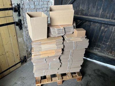 une pile de cartons posée sur une palette devant la porte d'un garage