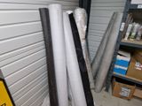 several rolls of white and black vinyl are stacked up in a storage room