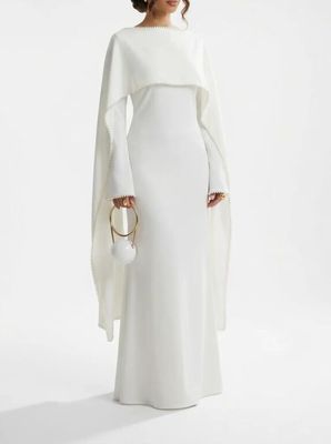 une femme en robe blanche, avec une cape sur les épaules