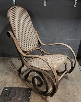 a rocking chair that has a wicker seat on it