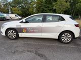 a white car parked in a parking lot with trees in the background