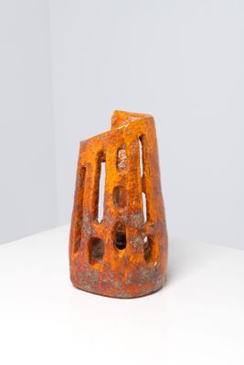an orange vase sitting on top of a white table