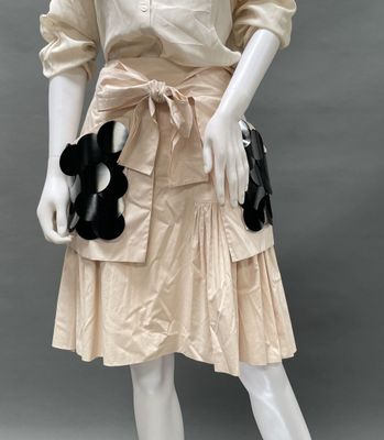 an image of a mannequin dressed in a beige dress with a black flower on it