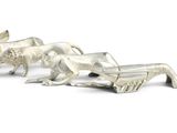 three silver figurines of animals on a white surface