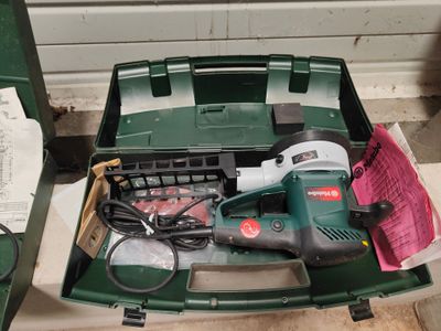 une boîte à outils verte posée par terre, contenant des outils