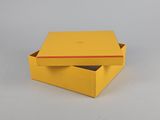 un gros plan d'une boîte jaune posée sur une surface blanche