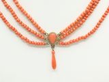 a close up of a necklace with coral beads on a mannequin