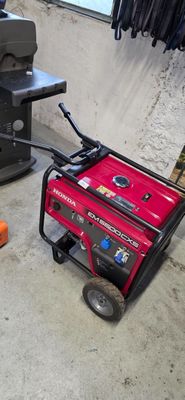 a small red generator sitting on the floor next to a printer