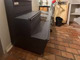 a black filing cabinet in the corner of a room