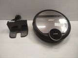 a black and silver robot sitting on a table next to a charger