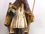 figurine représentant un homme coiffé d'un chapeau et vêtu d'une robe, tenant une canne