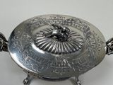 a silver plate with a bird on it on a stand