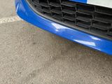 a close up of a car ' s grille with a blue car in the background
