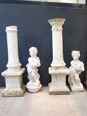 three white statues of children sitting on top of a stone pillar