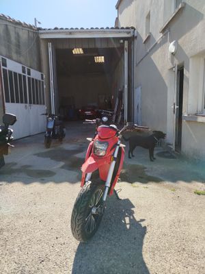 a red motorcycle parked in front of a garage