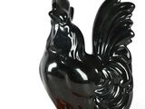 black rooster figurine on orange base on white background