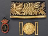 a black and gold purse with a gold leaf and a red and black badge