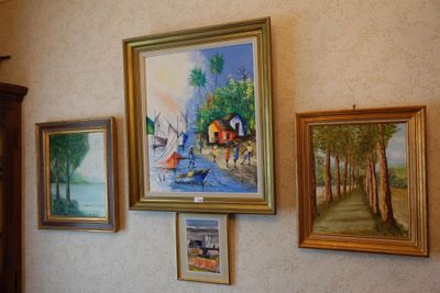 many paintings hanging on the wall of this room