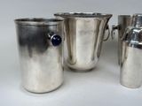 three silver vases with handles and a blue knob on a white surface