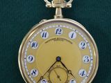 une montre de poche en or posée sur un tissu vert