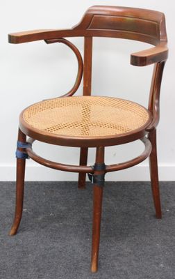 une chaise en bois avec une assise tressée, posée à même le sol