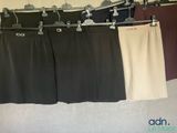 trois paires de pantalons suspendues à un portant dans une pièce