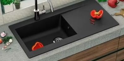 un évier de cuisine noir avec un robinet noir et une corbeille de fruits posée sur le plan de travail