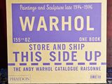 une pancarte sur laquelle on peut lire « Warhol, ce côté vers le haut » posée sur une table