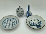 trois assiettes bleues et blanches et deux vases posés sur une table