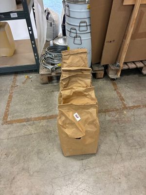 un sac en papier brun posé par terre à côté d'une pile de cartons