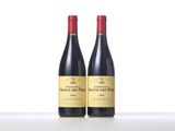 two bottles of red wine sitting on top of a table