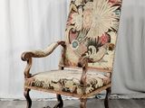 une vieille chaise avec un dossier et des accoudoirs tapissés de fleurs