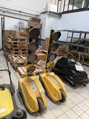 many pallets and boxes in a warehouse with a man on a mower